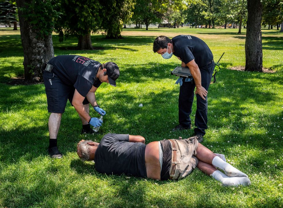 PHOTO: With the temperature well over 100 degrees, Spokane, Wash., firefighters check on the welfare of a man in Mission Park in Spokane, Wash., Tuesday, June 29, 2021.