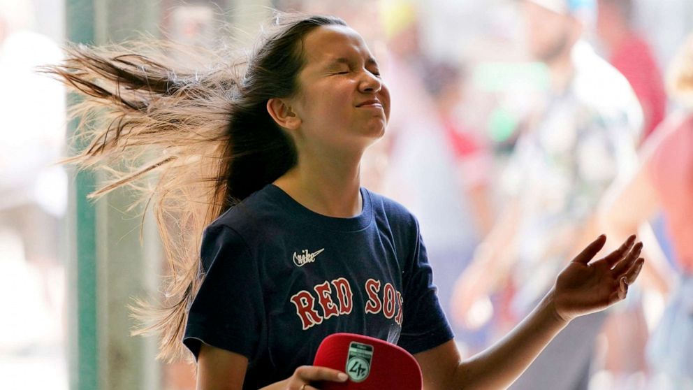 PHOTO: A Boston Red Sox's fan cools off in front of a misting fan at Fenway Park where a heat advisory was in effect before a baseball game against the Seattle Mariners, May 21, 2022, in Boston.