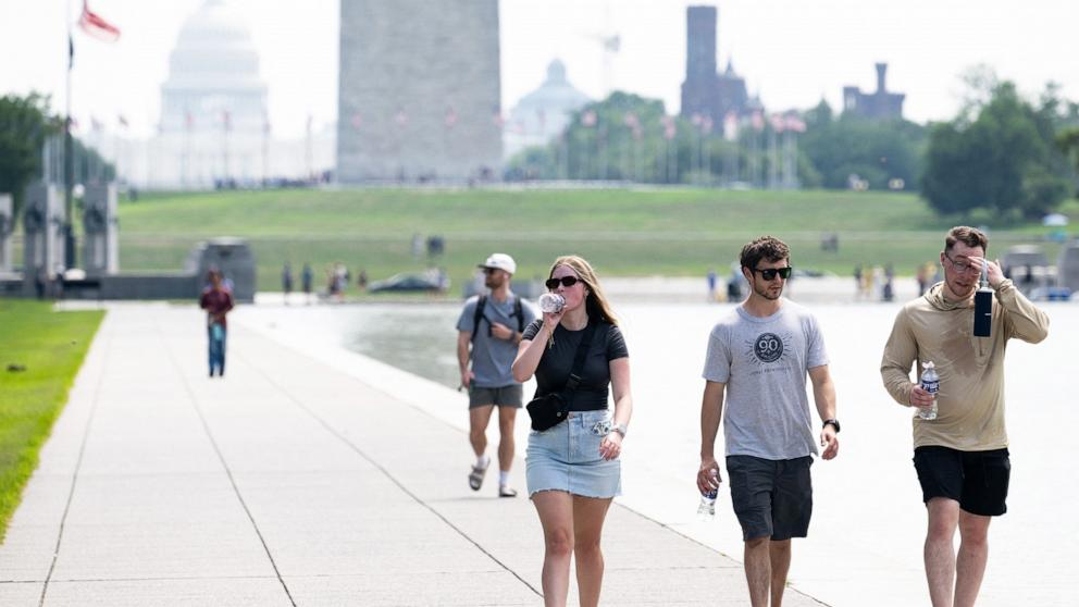 PHOTO: Tourists drink water as they walk along the National Mall near the Washington Monument in Washington, D.C., July 25, 2025, as a heat dome sits over the region leading to extremely high temperatures.
