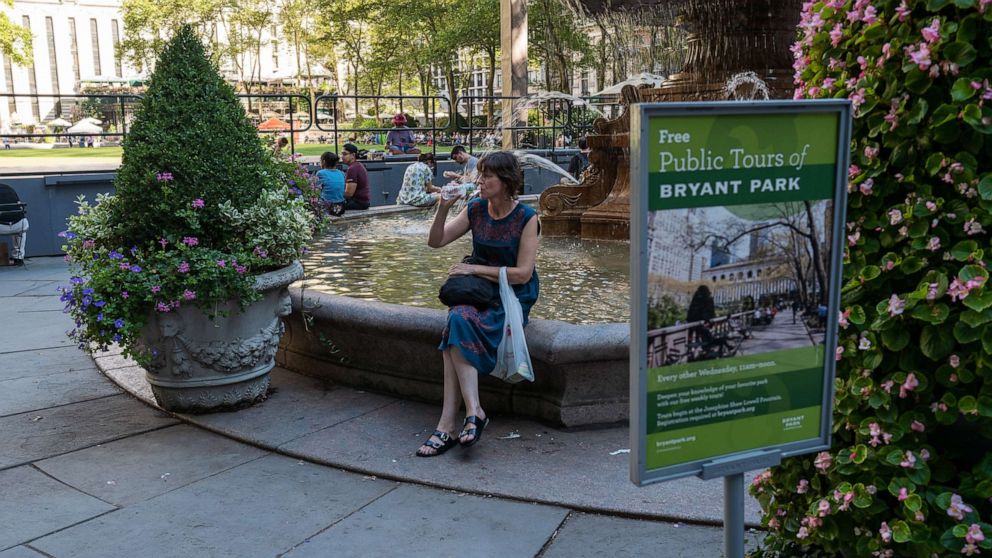 PHOTO: A woman drinks water while sitting in the shade in Bryant Park in midtown Manhattan on August 3, 2022 in New York City.