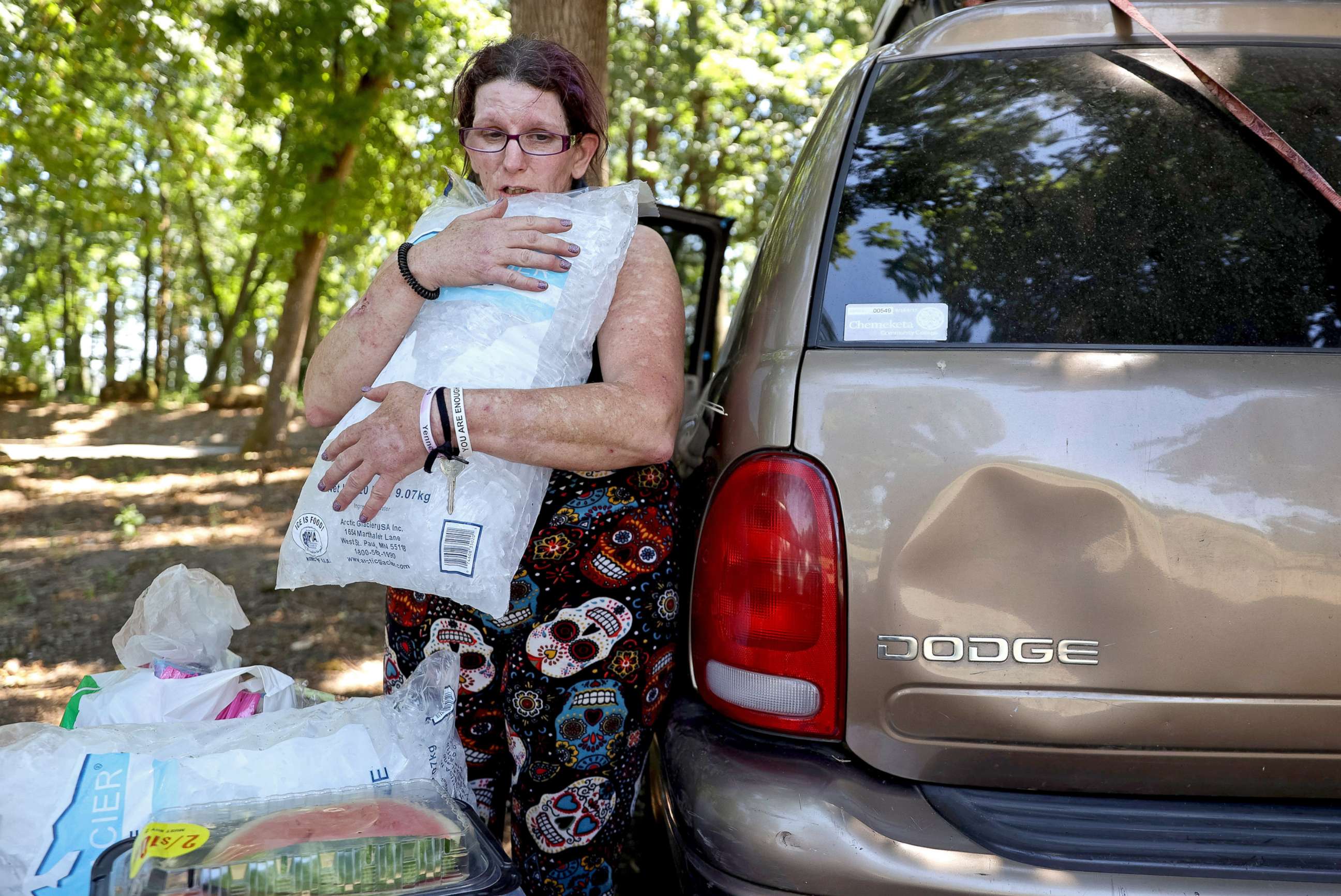 PHOTO: Carleen Bell hugs a bag of ice to cool off while unloading groceries at Wallace Marine Park in Salem, Ore., June 26, 2021.