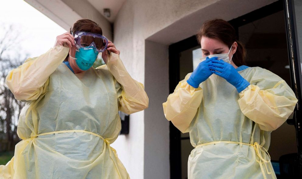 PHOTO: Health care workers from Virginia Hospital Center put on their personal protective equipment before people arrive at a drive-through testing site for the novel coronavirus in Arlington, Virginia, on March 20, 2020.