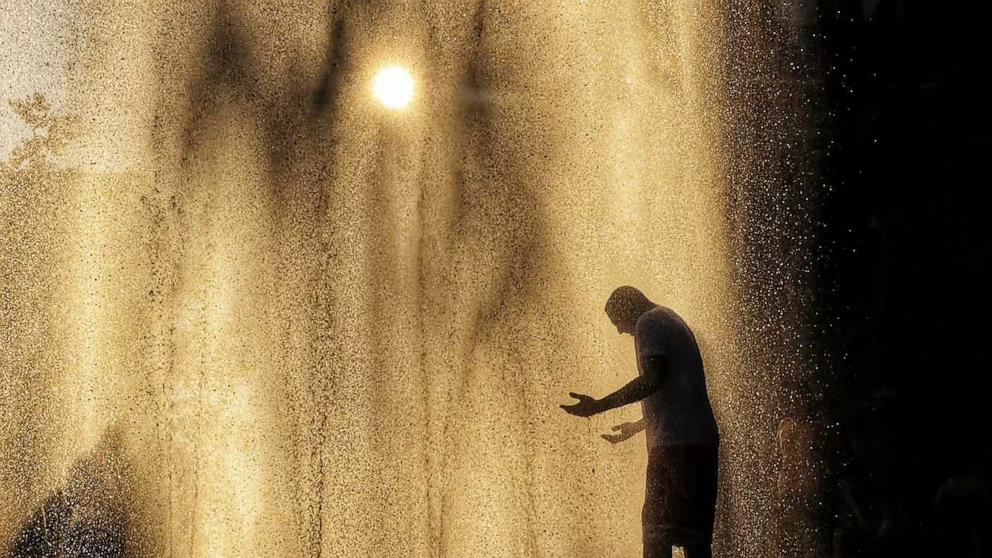 PHOTO: A man cools off in a fountain as the sun sets on June 20, 2024, in Hoboken, New Jersey. 