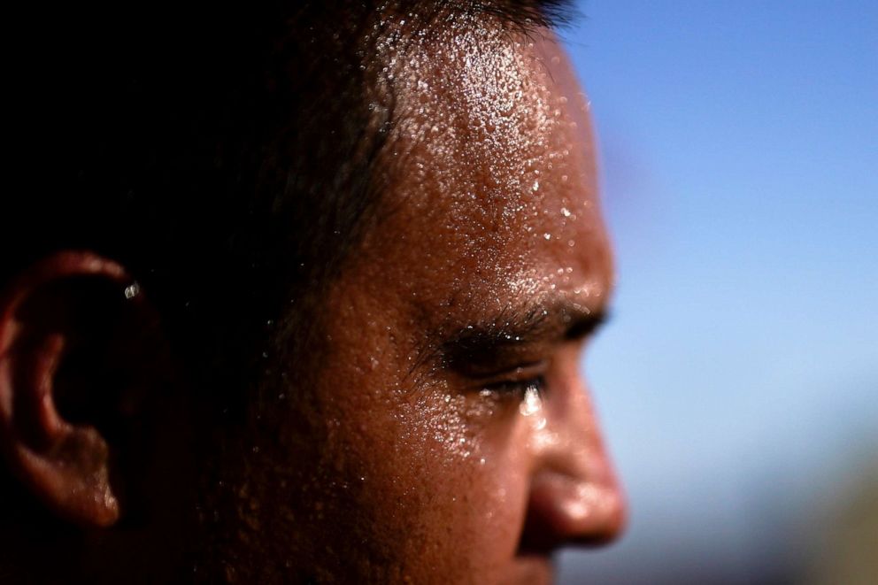 PHOTO: Sweat covers the face of Juan Carlos Biseno after dancing to music from his headphones as afternoon temperatures reach 115 degrees Fahrenheit, July 19, 2023,