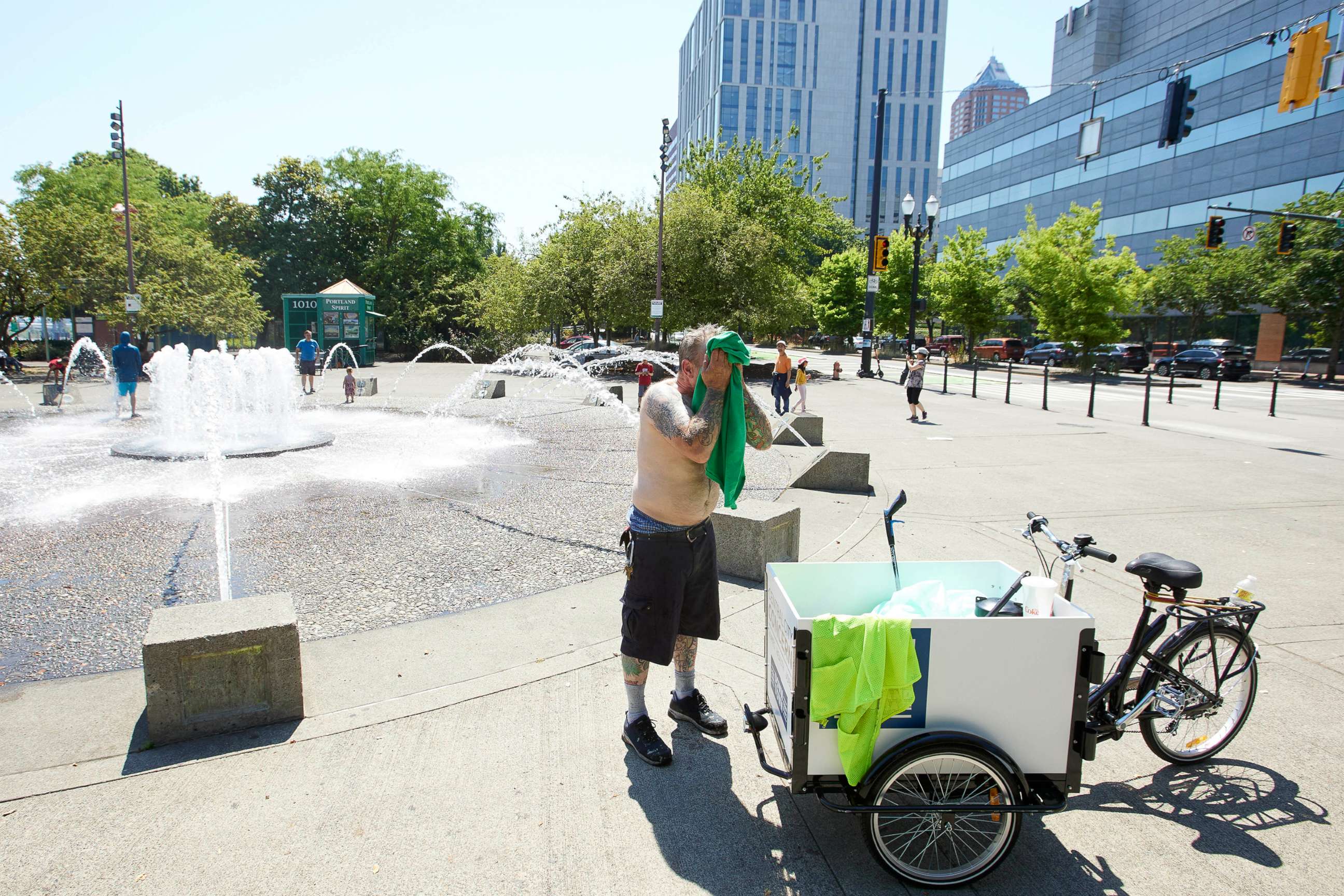 PHOTO: Matthew Carr dries himself after cooling off in the Salmon Street Springs fountain before returning work cleaning up trash on his bicycle in Portland, Ore., July 26, 2022