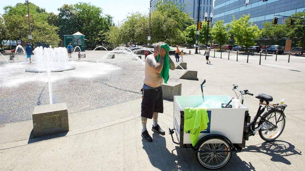 PHOTO: Matthew Carr dries himself after cooling off in the Salmon Street Springs fountain before returning work cleaning up trash on his bicycle in Portland, Ore., July 26, 2022