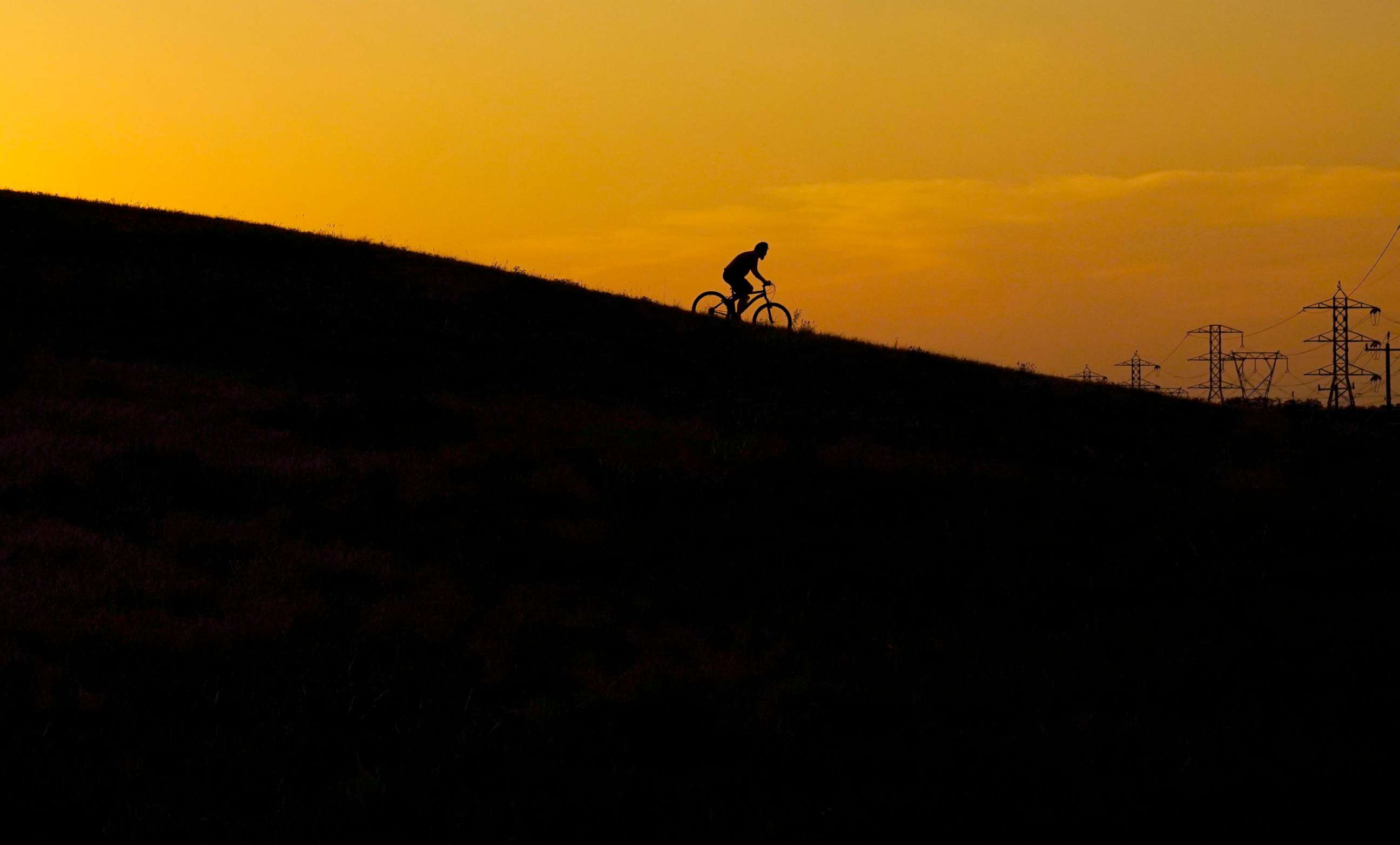PHOTO: A cyclist rides through a park at sunset as temperatures in South Texas continue to top the 100 degree mark in San Antonio, Texas, June 8, 2022.