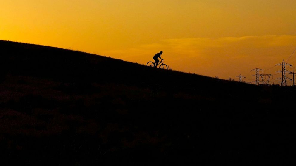 PHOTO: A cyclist rides through a park at sunset as temperatures in South Texas continue to top the 100 degree mark in San Antonio, Texas, June 8, 2022.