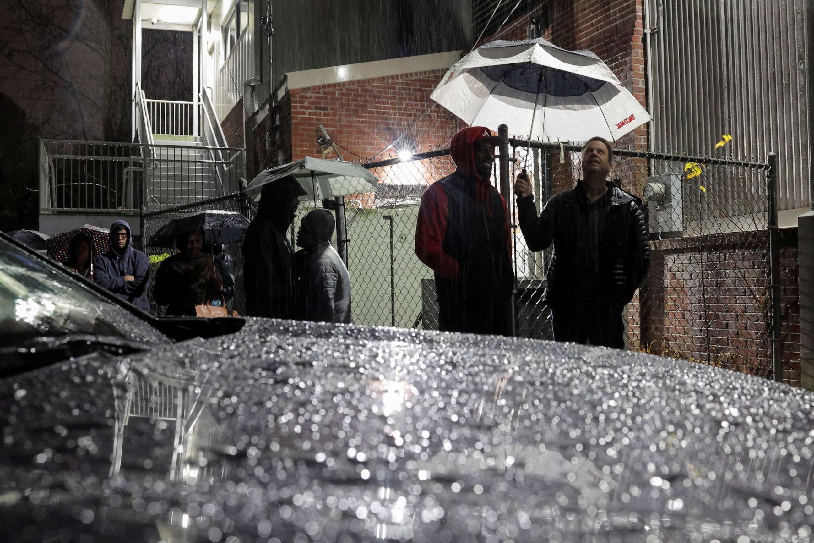 PHOTO: Local residents stand under the rain as they wait in line to cast their ballot during the runoff U.S. Senate election in Atlanta, December 6, 2022.