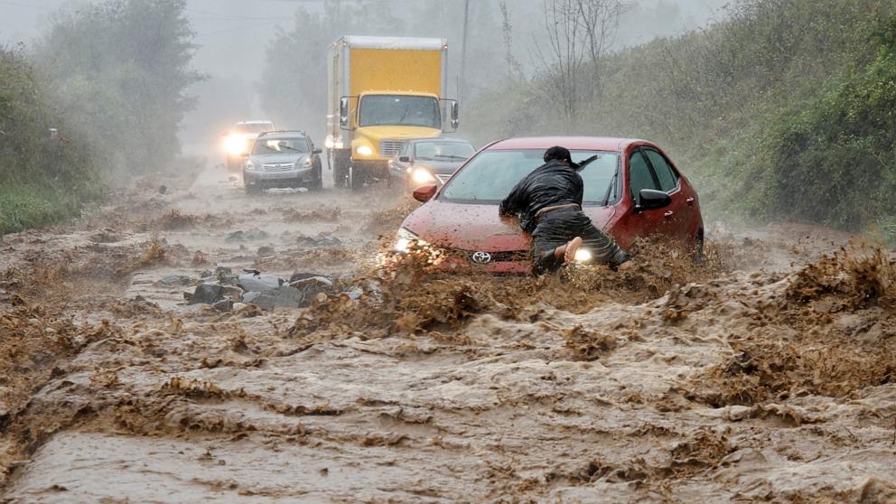 PHOTO: A local resident helps free a car that became stranded in a stretch of flooding road as Tropical Storm Helene strikes, on the outskirts of Boone, North Carolina, Sept. 27, 2024. 