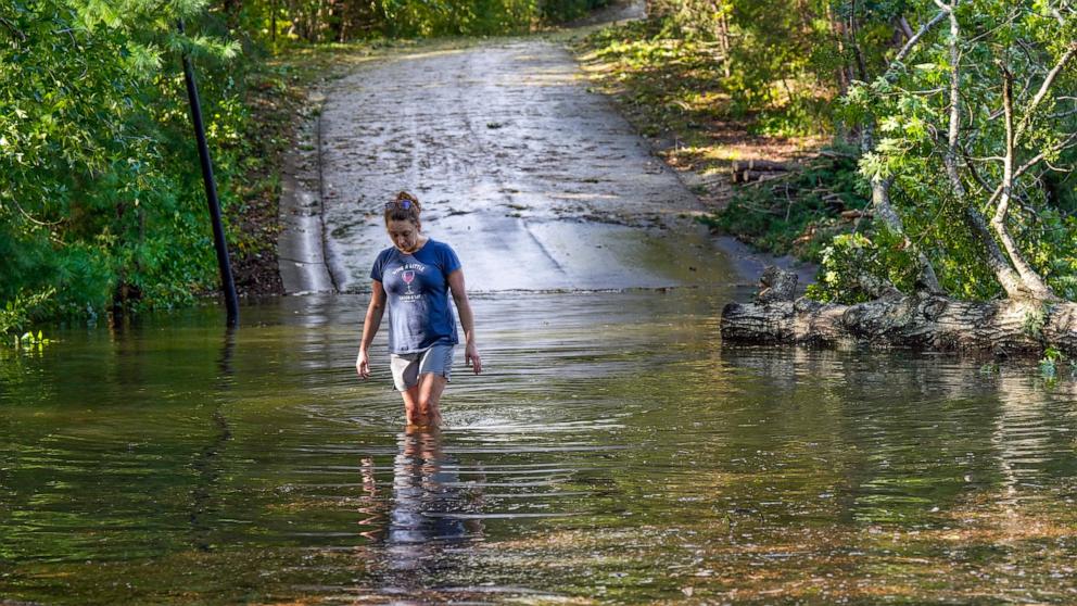 PHOTO: Teresa Elder walks through a flooded Sandy Cove Drive,  from Hurricane Helene, Sept. 27, 2024, in Morganton, N.C.  