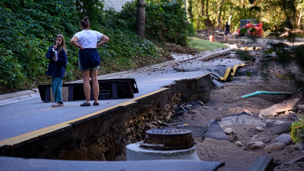 PHOTO: Residents walk along Flat Creek Road, which was partially washed out and impassable from flood waters, Oct. 2, 2024, in Black Mountain, North Carolina. 