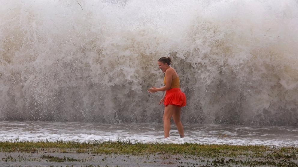 PHOTO: Tanner Flynn stands in shallow water near crashing waves as Hurricane Helene passes offshore, Sept. 26, 2024, in St. Petersburg, Fla. 