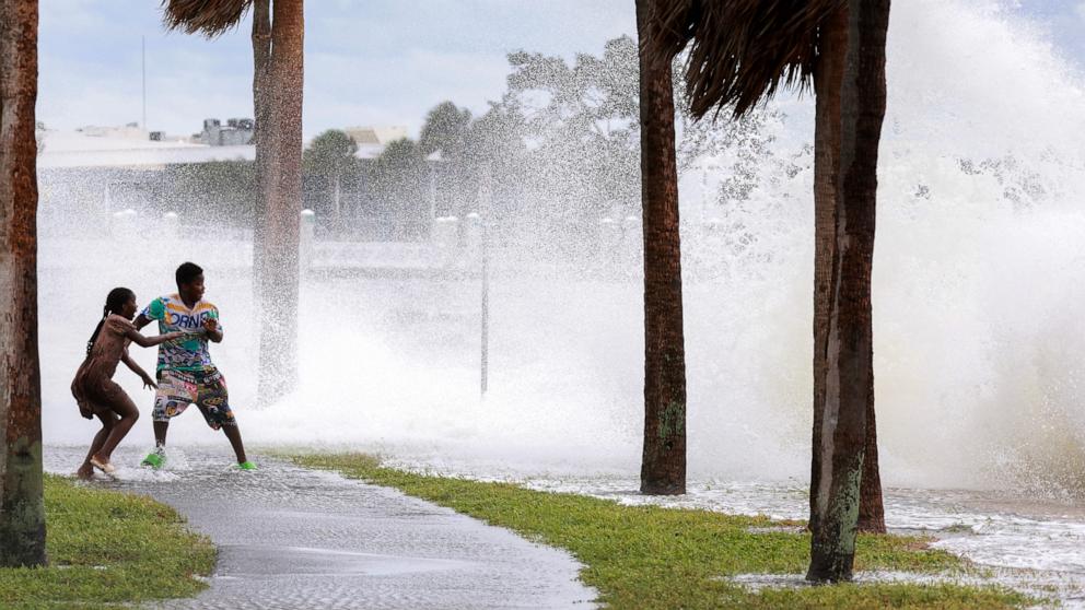 PHOTO: People are splashed by churning surf from Tampa Bay as Hurricane Helene passes offshore, Sept. 26, 2024, in St. Petersburg, Fla.