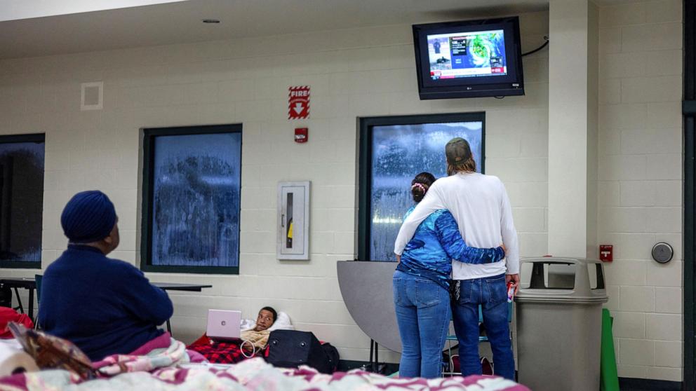 PHOTO: Douglas Gajus and his wife Tara watch the news as they wait for the arrival of Hurricane Helene at Lincoln High School which was opened as a shelter in Tallahassee, Fla., on Sept. 26, 2024.