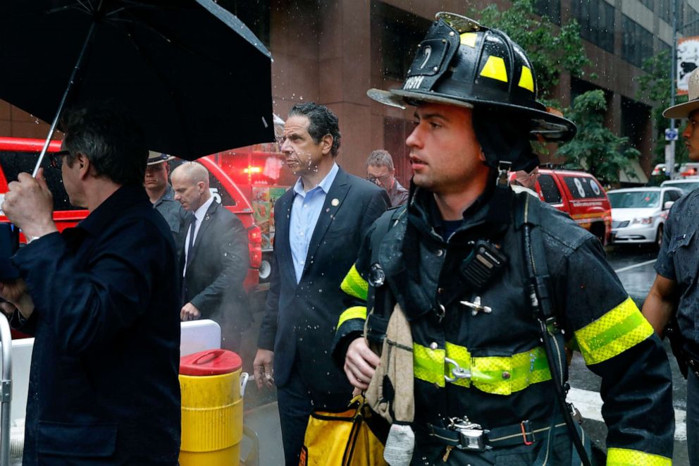 PHOTO: New York Gov. Andrew Cuomo, center, and first responder personnel walk near the scene where a helicopter was reported to have crash landed on top of a building in midtown, June 10, 2019, in New York.