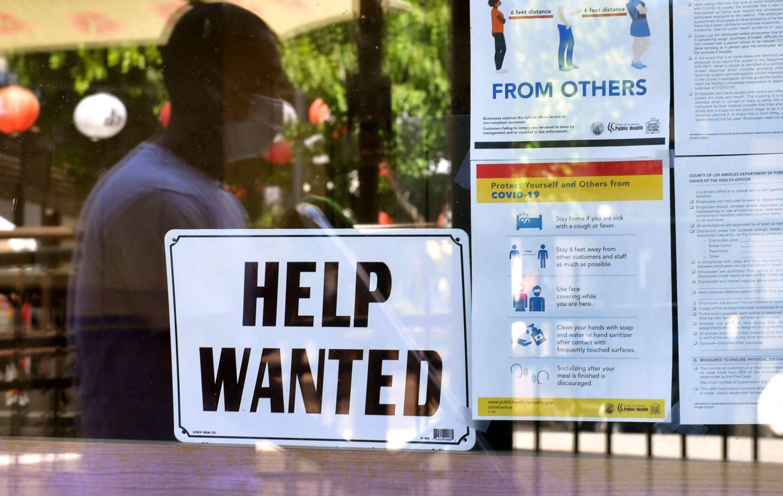 PHOTO: In this May 28, 2021, file photo, a 'Help Wanted' sign is posted beside Coronavirus safety guidelines in front of a restaurant in Los Angeles.