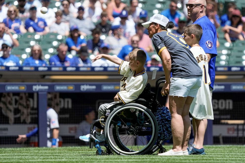 PHOTO: Highland Park shooting victim Cooper Roberts throws out a ceremonial first pitch before a baseball game between the Milwaukee Brewers and the Chicago Cubs, July 3, 2023, in Milwaukee.