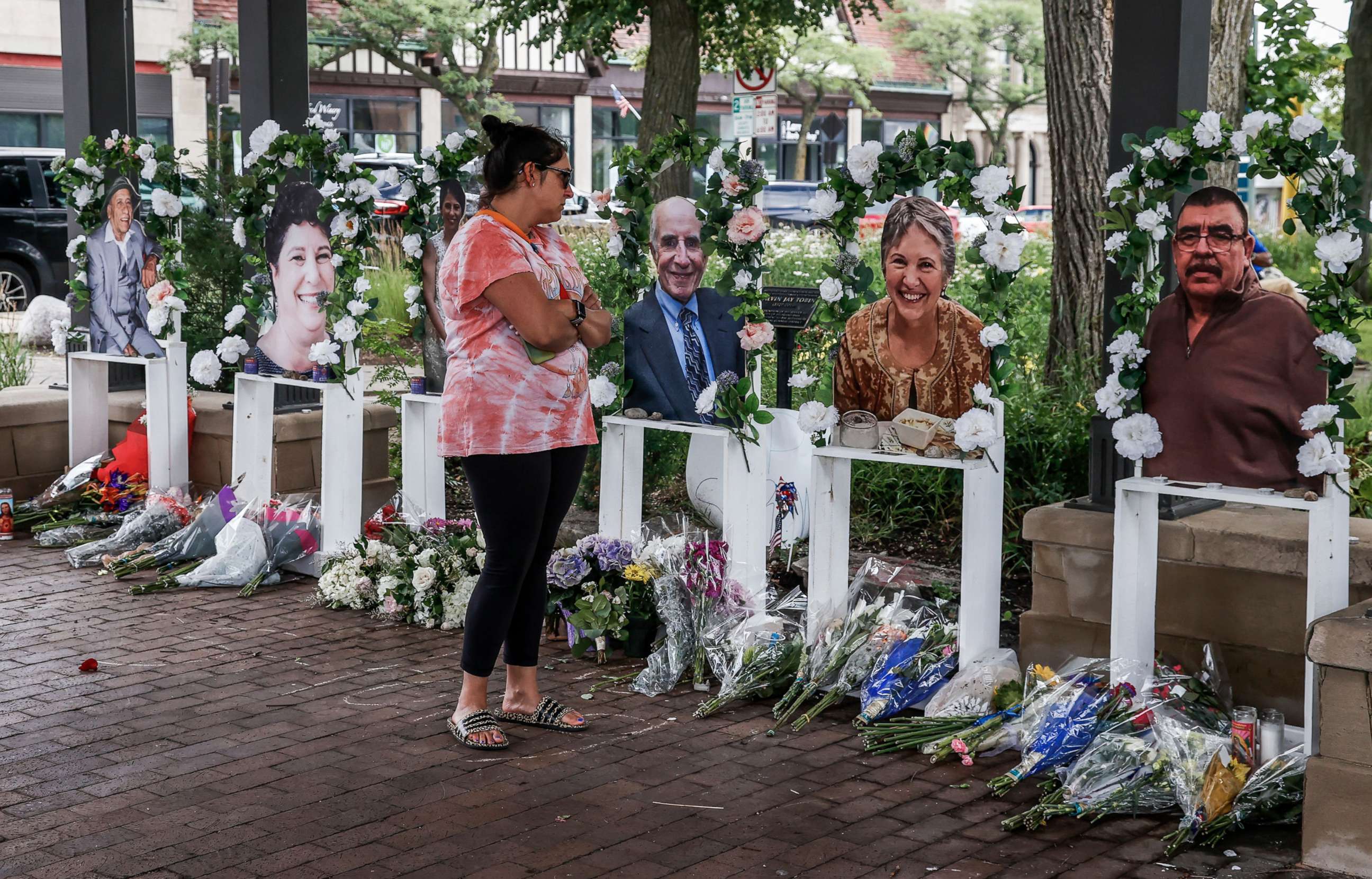 PHOTO: A woman looks a photographs of victims at a memorial near the scene of a mass shooting that took place at a 4th of July celebration and parade in Highland Park, Ill., July 7, 2022.