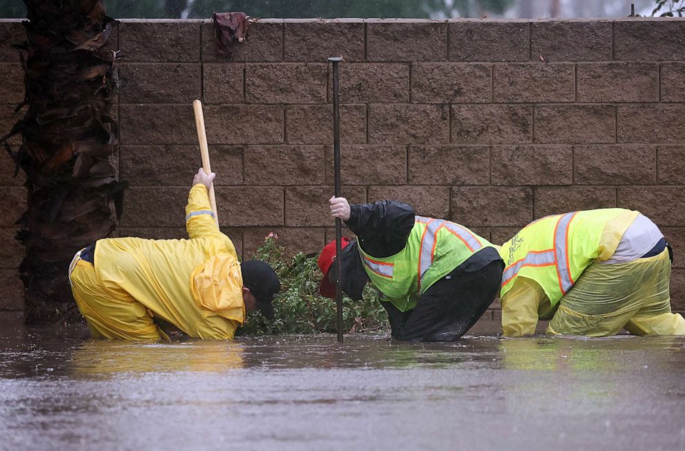 PHOTO: Workers attempt to unclog a drain on a flooded street as Tropical Storm Hilary moves through the area on Aug. 20, 2023, in Rancho Mirage, Calif.