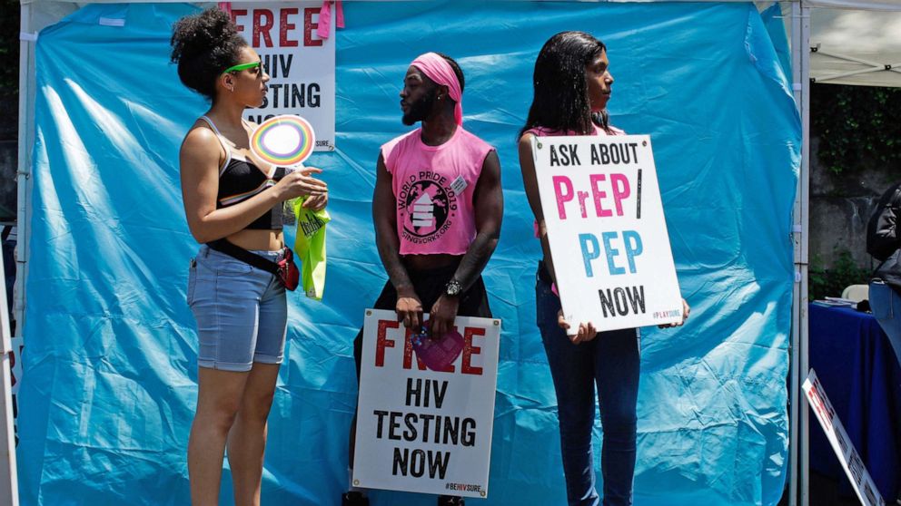 PHOTO: Volunteers hold signs as they promote free HIV testing and PrEP during the Harlem Pride parade in New York, June 29, 2019.