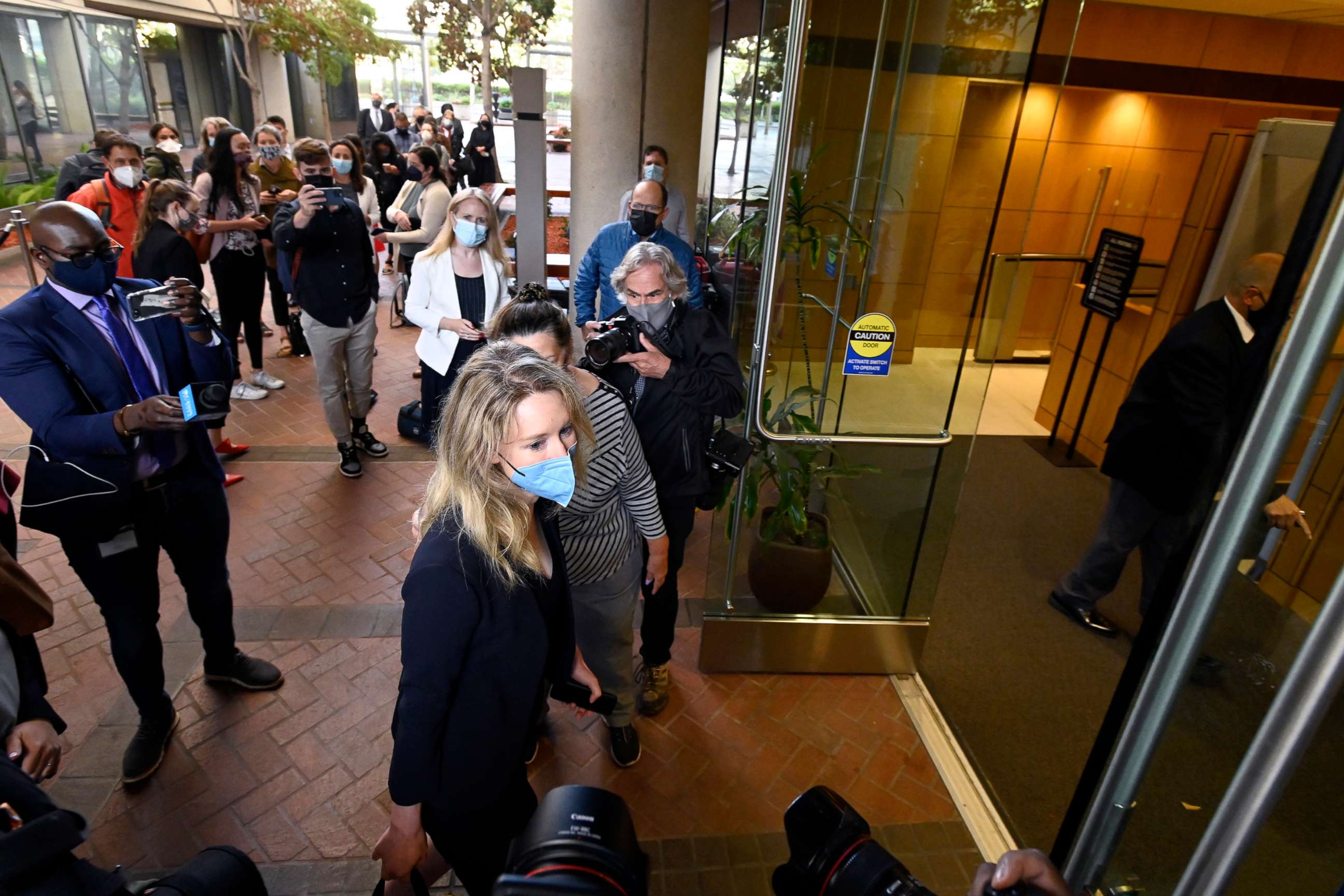 PHOTO: Elizabeth Holmes, bottom center, founder and CEO of Theranos, arrives at the federal courthouse for jury selection in her trial, Aug. 31, 2021, in San Jose, Calif.
