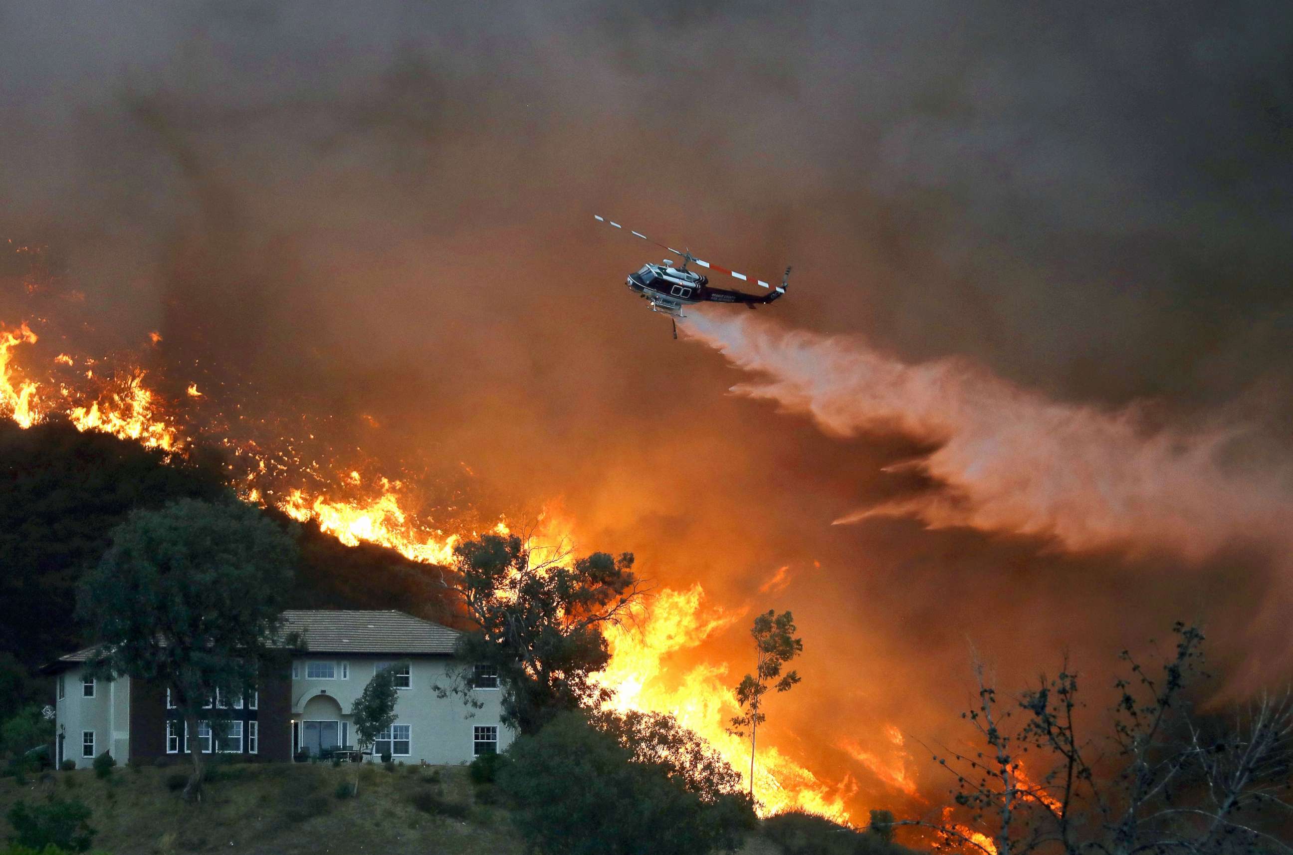 PHOTO: A firefighting helicopter makes a water drop as the Holy Fire burns near homes, Aug. 9, 2018, in Lake Elsinore, Calif.