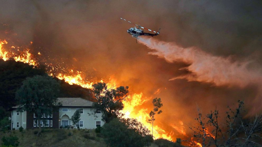 PHOTO: A firefighting helicopter makes a water drop as the Holy Fire burns near homes, Aug. 9, 2018, in Lake Elsinore, Calif.