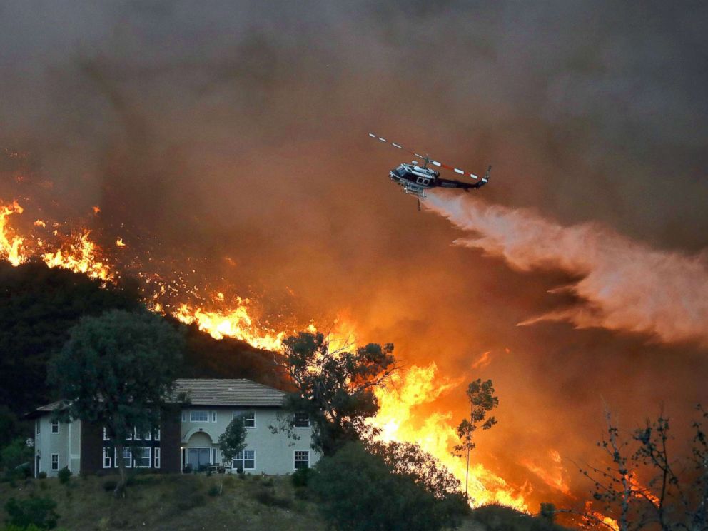 PHOTO: A firefighting helicopter makes a water drop as the Holy Fire burns near homes, Aug. 9, 2018, in Lake Elsinore, Calif.
