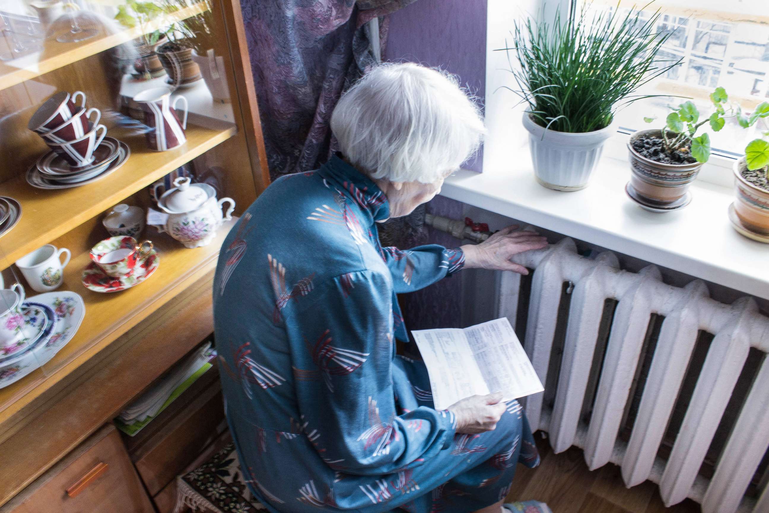 PHOTO: A senior woman holding gas bill in front of heating radiator in an undated stock image.