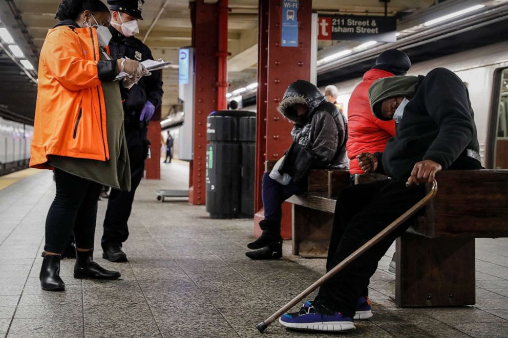 PHOTO: FILE - A homeless outreach worker and New York police officer assist passengers found sleeping on subway cars at the 207th Street A-train station, April 30, 2020, in the Manhattan borough of New York.