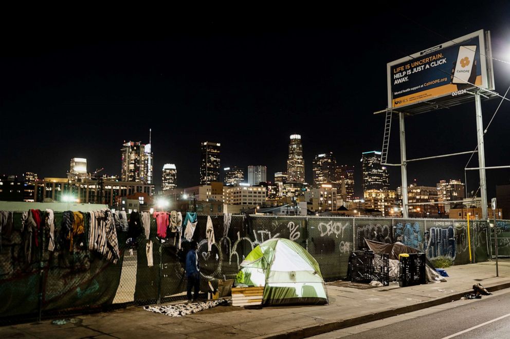 PHOTO:In this photo illuminated by an off-camera flash, a homeless person's tent is backdropped by the skyline of Los Angeles, Feb. 8, 2023.