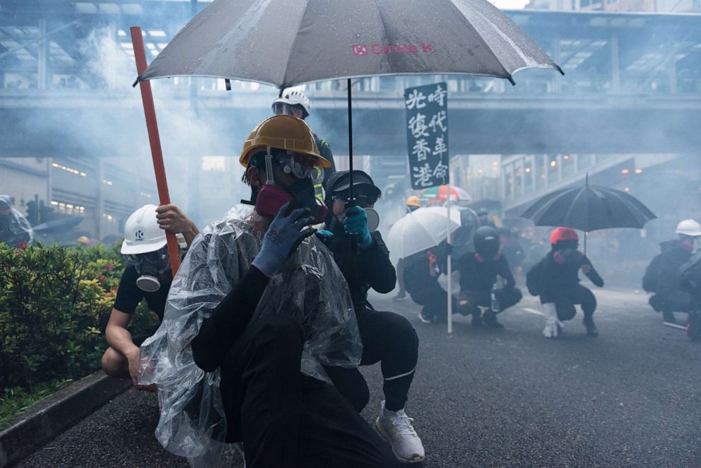 PHOTO: Protesters take cover as tear gas is being fired towards them by the police during the demonstration, Hong Kong, China, August 25, 2019.