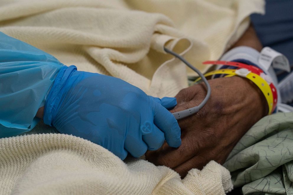 PHOTO: A medical staff member holds a hand of a patient in the COVID-19 intensive care unit at the United Memorial Medical Center on Nov. 19, 2020, in Houston.