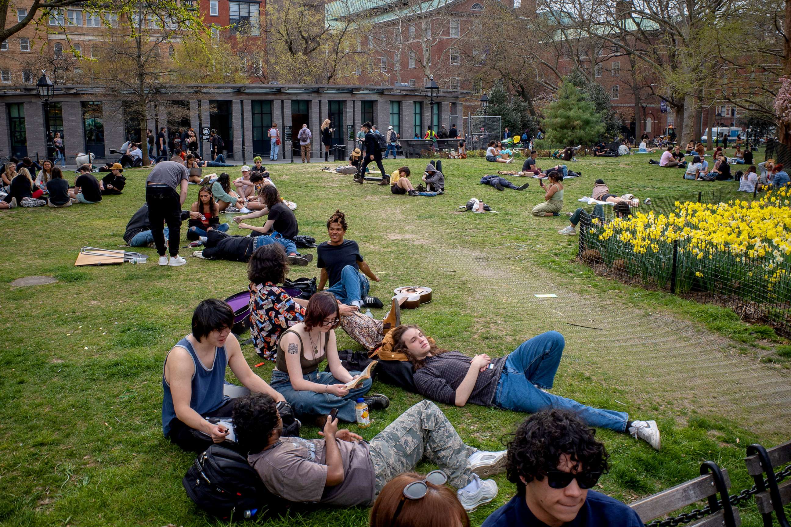 PHOTO: People gather on the grass field at Washington Square Park as tulips bloom in New York City, April 11, 2023.