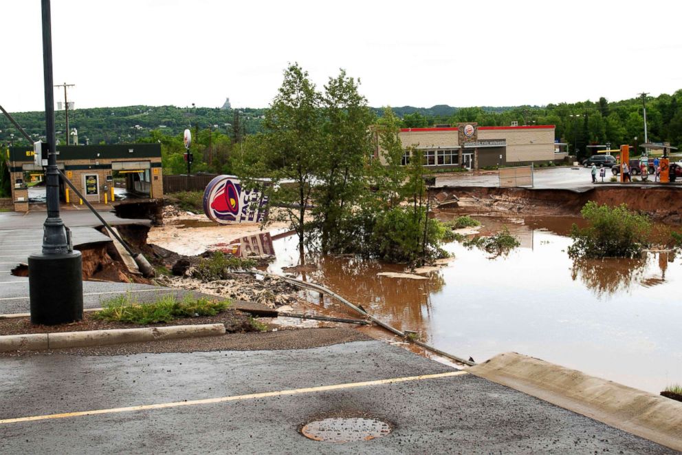 PHOTO: People view where a Taco Bell drive-through caved in and washed away after heavy rains and flooding in Houghton, Mich., June 17, 2018.