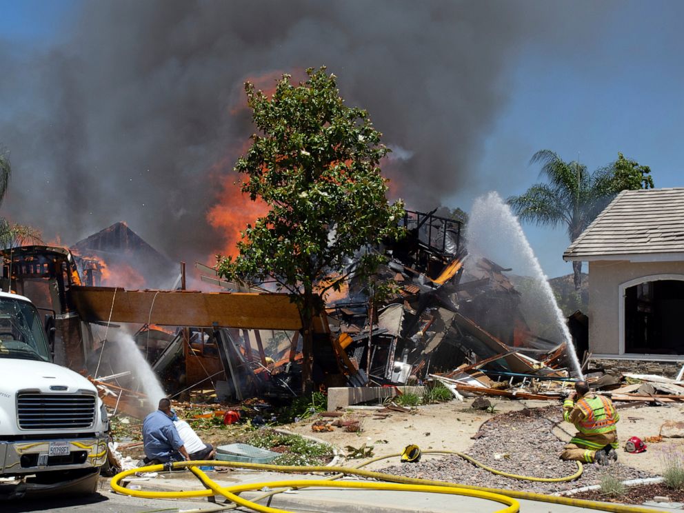 PHOTO: A firefighter and civilians train fire hoses on a burning home after an explosion and fire destroyed the home in Murrieta, Calif., sending up thick flames and closing several streets.