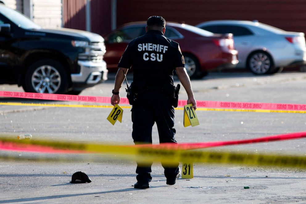 PHOTO: A police officer investigates a crime scene where two people were killed and three more critically injured in a shooting at a flea market in Houston on May 15, 2022. 