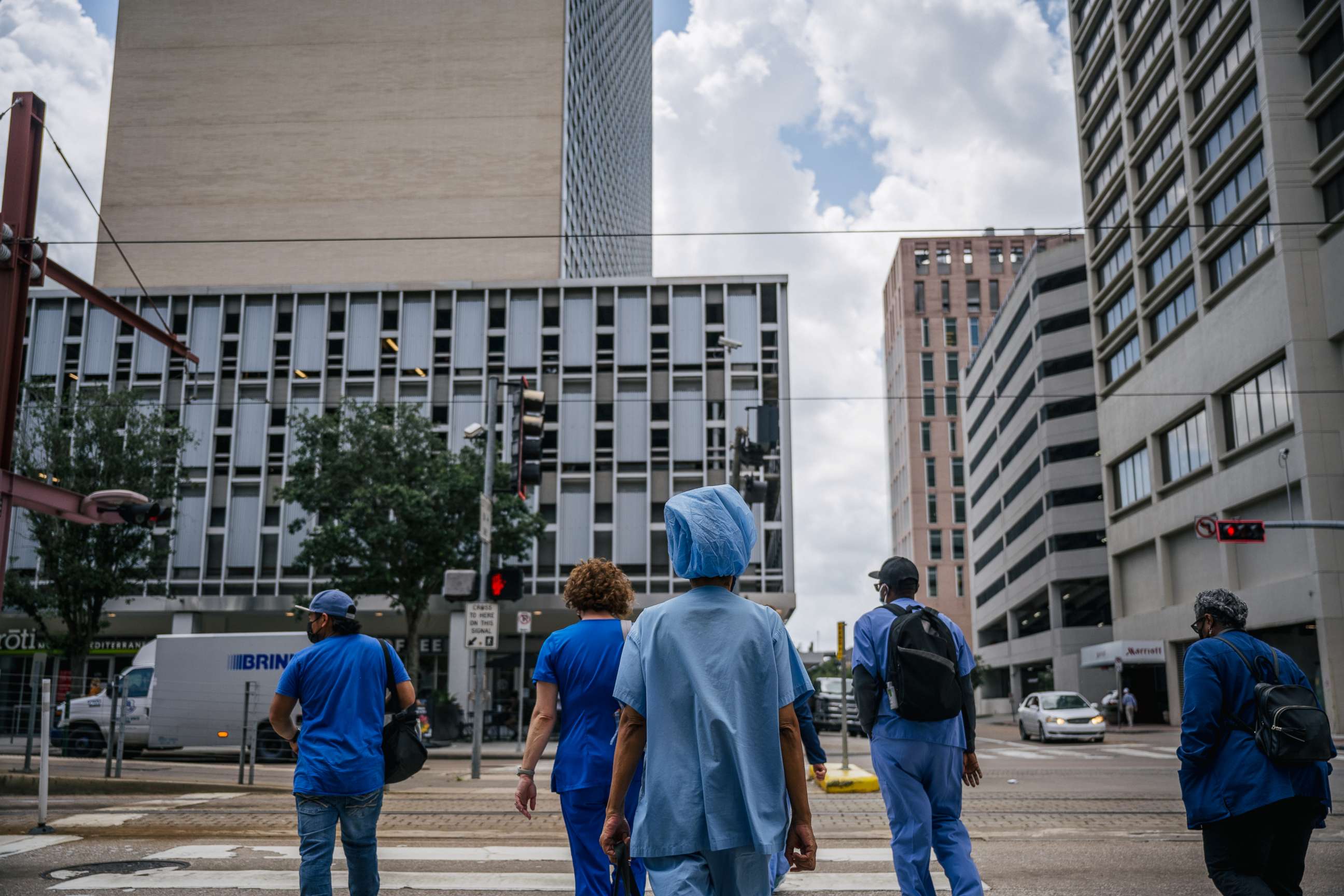 PHOTO: Medical workers and pedestrians cross an intersection outside of the Houston Methodist Hospital on June 09, 2021, in Houston.