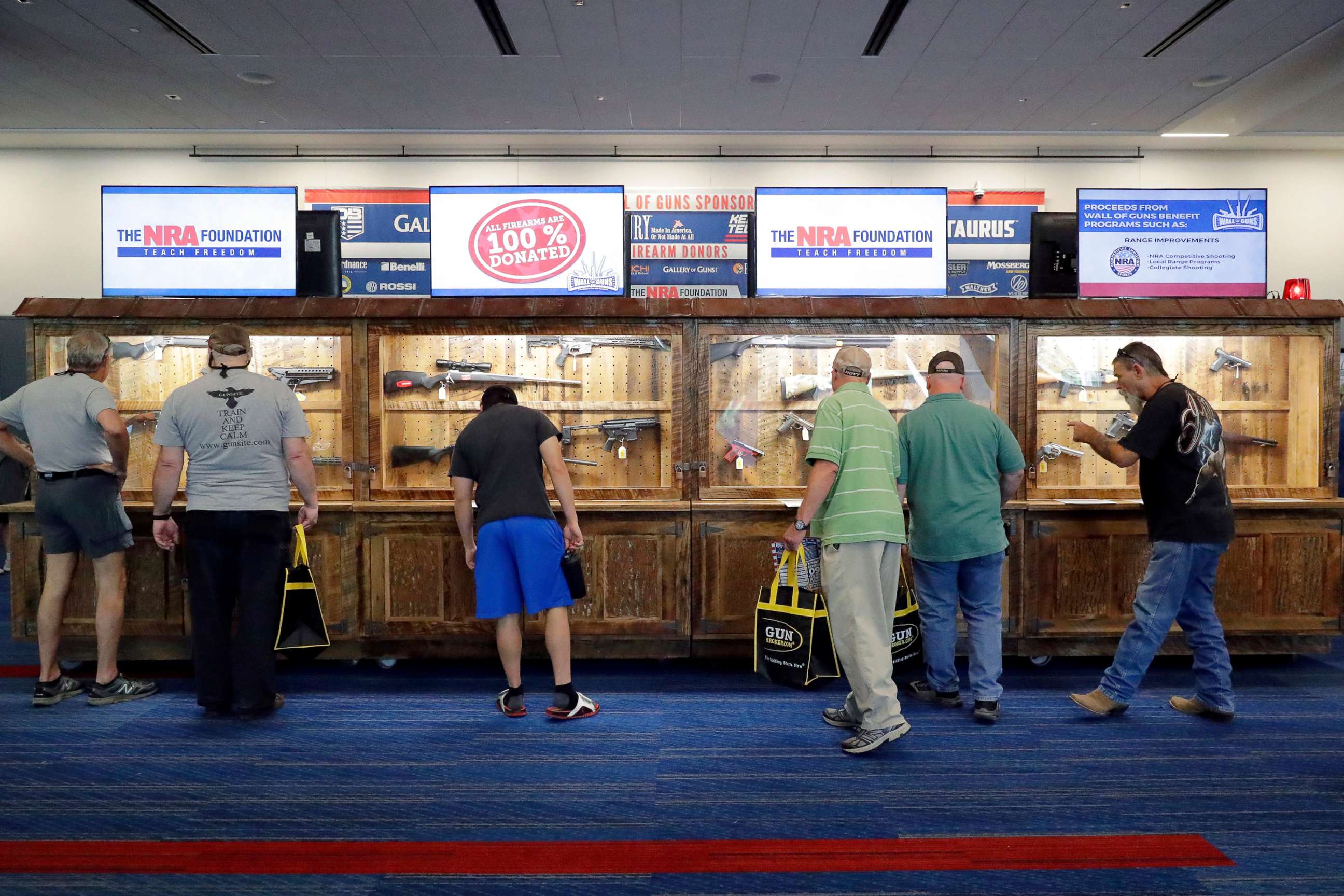 PHOTO: Convention attendees look at various rifles and handguns in display cases that will be raffled off at the Gallery of Guns booth at the NRA Annual Meeting held at the George R. Brown Convention Center, on May 26, 2022, in Houston.