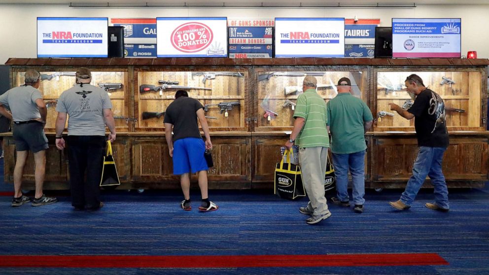 PHOTO: Convention attendees look at various rifles and handguns in display cases that will be raffled off at the Gallery of Guns booth at the NRA Annual Meeting held at the George R. Brown Convention Center, on May 26, 2022, in Houston.
