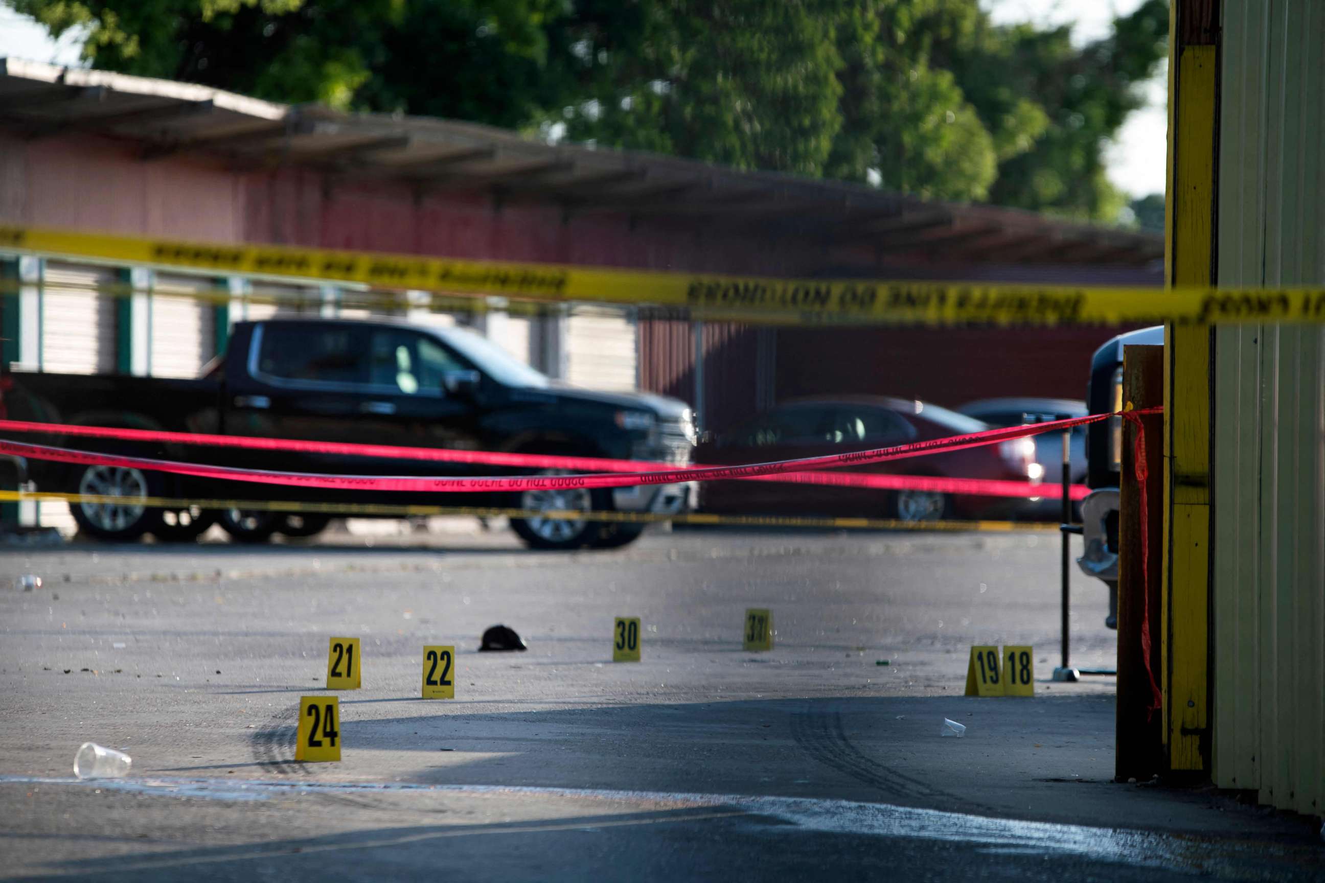 PHOTO: The scene of a shooting is pictured behind police yellow tape after two people were killed and three more critically injured in a shooting at a flea market in Houston, Texas on May 15, 2022.
