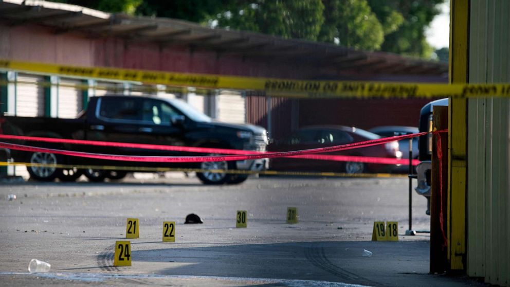 PHOTO: The scene of a shooting is pictured behind police yellow tape after two people were killed and three more critically injured in a shooting at a flea market in Houston, Texas on May 15, 2022.