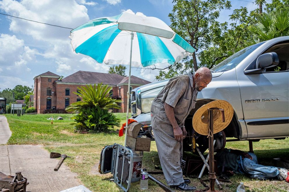 PHOTO: A mechanic works on a neighbors vehicle during a heatwave on July 21, 2022 in Houston.
