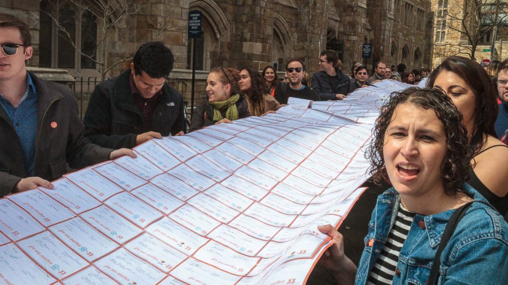 Protesters walk down College Street on Yale University campus in New Haven, Conn., holding signatures from a petition asking the school to engage in collective bargaining with the graduate student union, April, 2017.