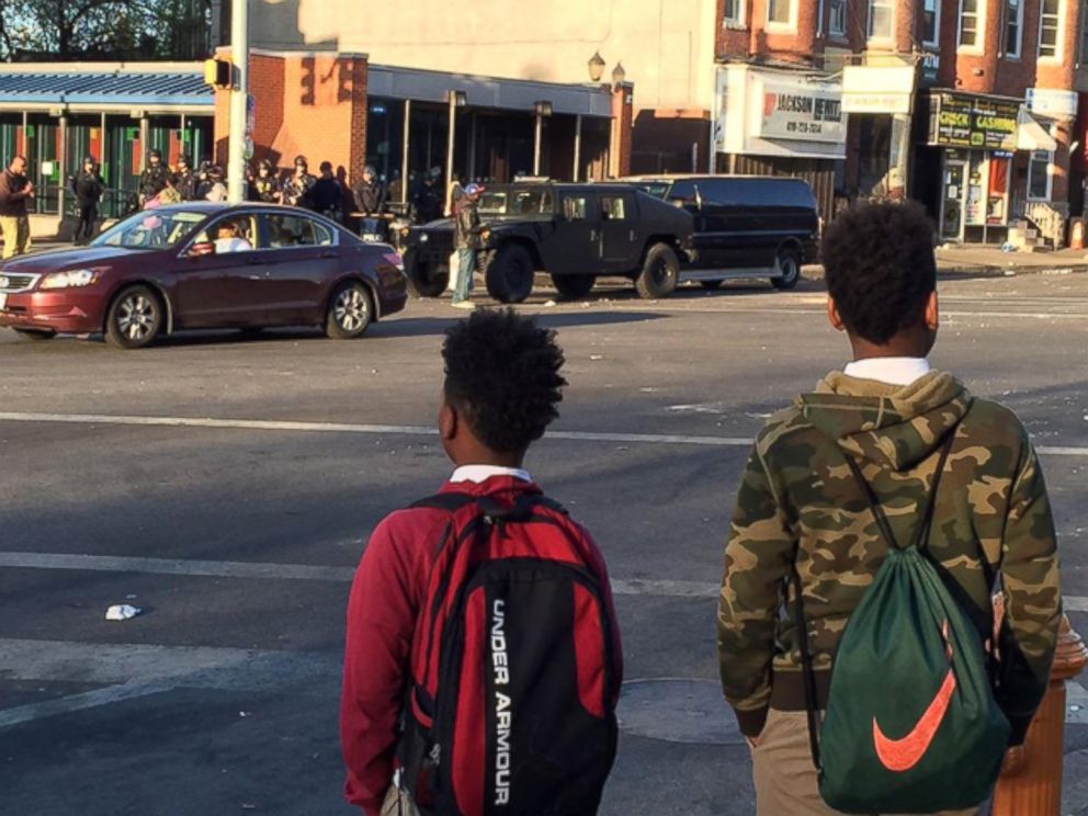 PHOTO: Kids on their way to school in Baltimore as riot police watch April 29, 2015. 