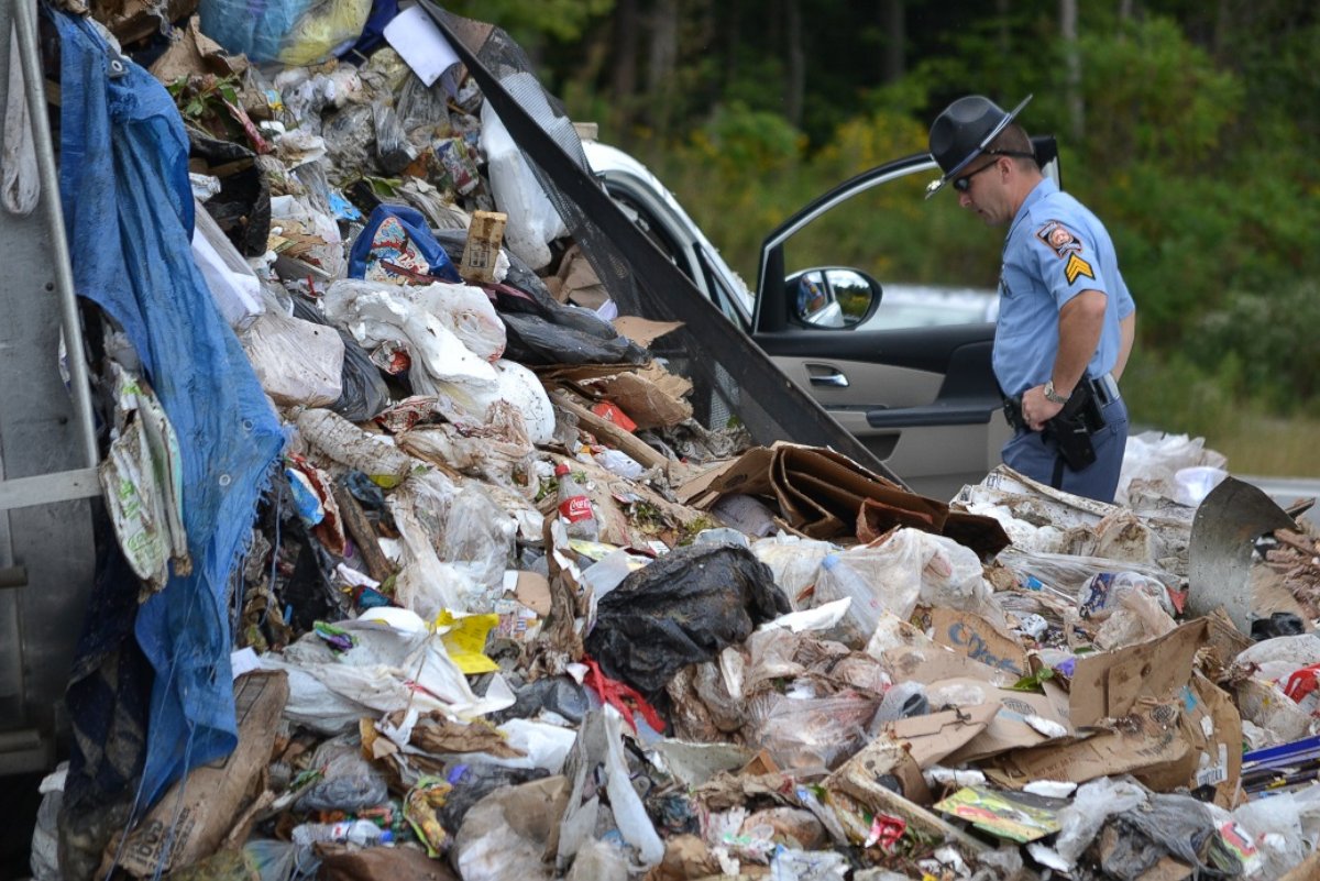PHOTO: Officials respond to a garbage truck that spilled mounds of garbage onto a minivan.