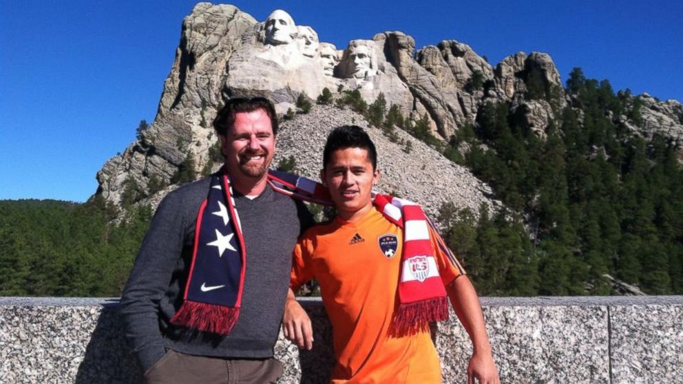 Jose, a teenager who was one of the hundreds of thousands of unaccompanied minors who arrived in the United States, was placed with a foster family in Michigan and has adapted to life in America. He is seen here with his foster father, Pete Homeyer, during a family trip to Mount Rushmore this summer. 