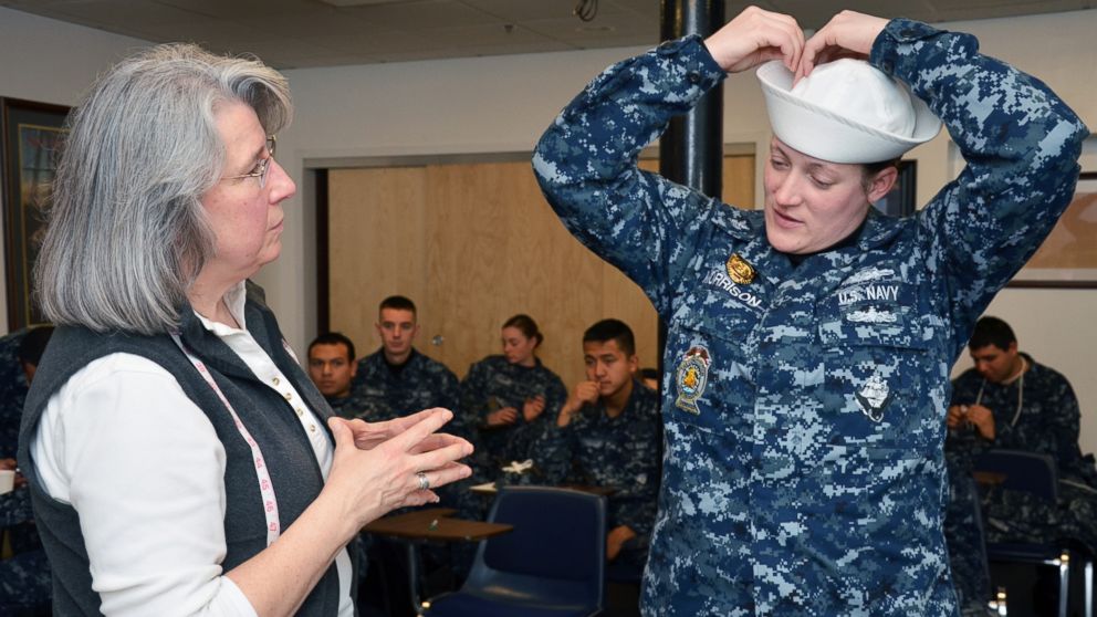 Master-at-Arms 1st Class Mary Morrison, from Mountain View, Oklahoma, assigned to USS Constitution, tries on a Navy white hat, or "Dixie cup" cover to be used for the new E1-E6 service dress blue female uniform with a uniform official during a fit evaluation., Feb. 6, 2015. 