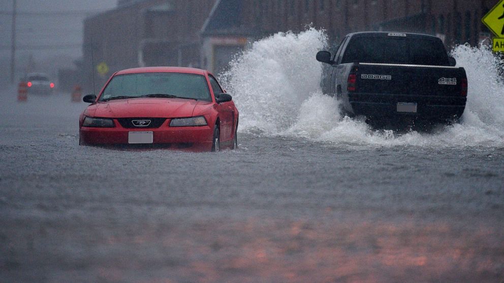 PHOTO: In this July 4, 2014, file photo, a pick-up truck makes its way pass an abandoned car in New Bedford, Mass., which were flooded by the heavy rains brought in by Hurricane Arthur.